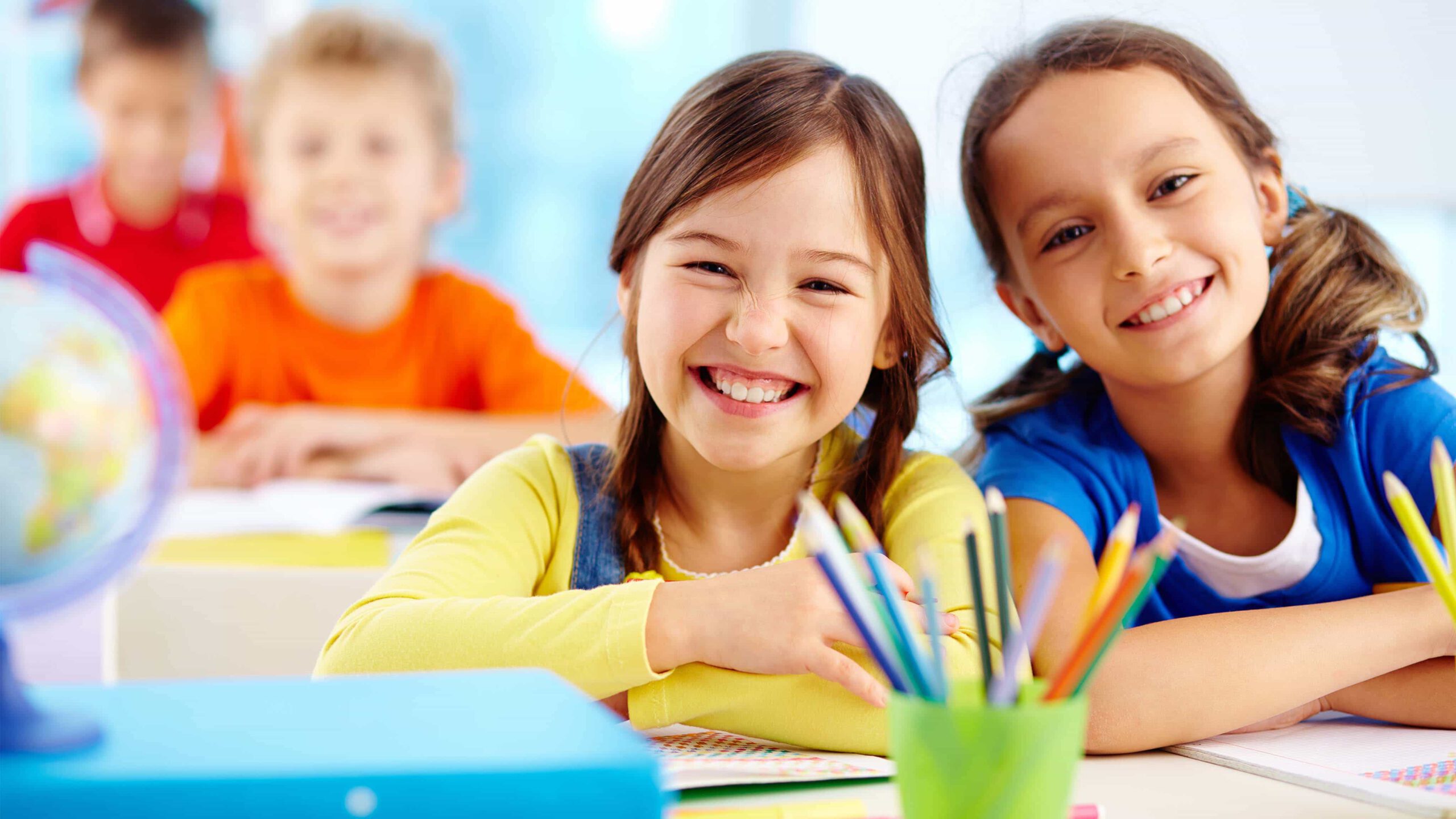 kinder sitzen im klassenzimmer und lächeln in die kamera